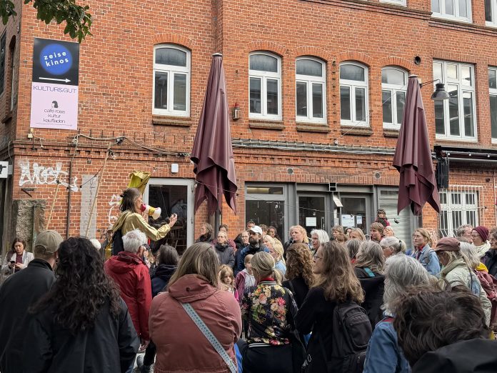IMG_1372 Eine Menschentraube steht im Hof der Zeisehallen und schaut zu einer Frau, die durch ein Megafon spricht.