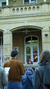 Singende Leute beim Mitmachchor. Die Leiterin Sasa Jansen ist in der Mitte auf der Veranda des HausDrei. 