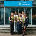 Preisverleihung beim Forschungstag der HAW Hamburg 5 Frauen mit einem Blumenstrauß stehen vor dem Eingang eines HAW-Gebäudes.