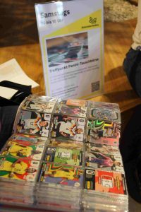 Ein Sammelalbum mit Panini-Sammelkarten liegt geöffnet vor einem Schild über eine Tauschbörse, die am Samstag stattfindet.