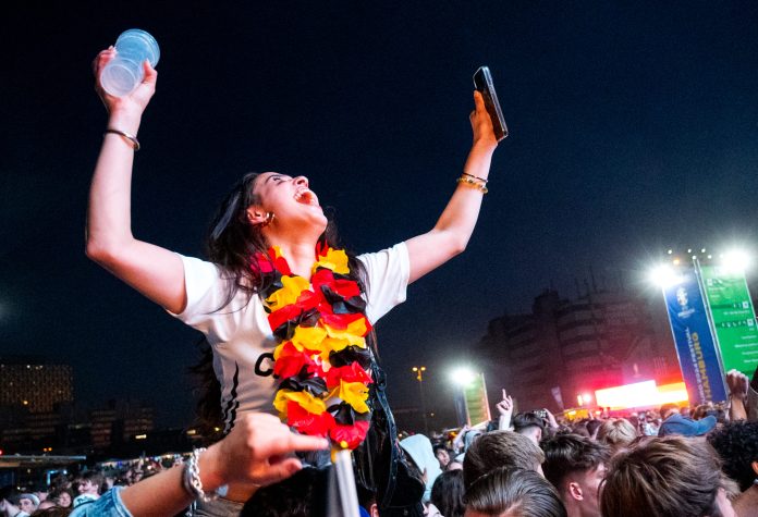 Junge Frau mit Deutschlandtrikot jubelt bei einem Public Viewing.