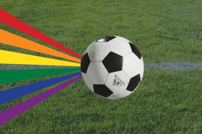 Ein Fußball ist auf Rasen zu sehen mit einer Regenbogenflagge. Die Regenbogenflagge steht unter anderen für queere Personen. Das Public-Viewing ist für sie ausgelegt.