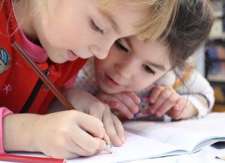 Neue Regeln für Schulbegleitung in Hamburg Zwei Kinder schauen auf ein Schulheft und schreiben darin.