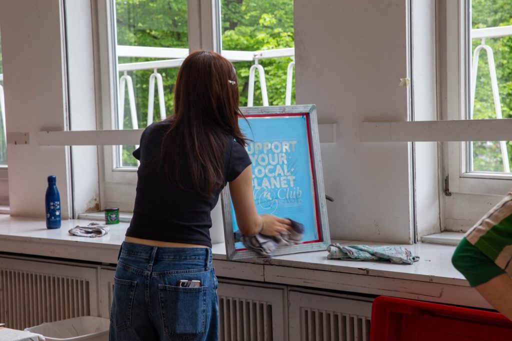 Eine Frau bereitet eine Vorlage für den Siebdruck bei der Kleidertauschparty vor.