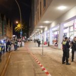 Messerattacke in Altonaer Supermarkt endet tödlich EIn Polizeiauto steht an einem Bürgersteig wo eine Gruppe an Polizist*innen vor einem Rewe stehen im Kontext einer Messerattacke