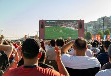 Hochbahn gönnt WM-Fans 20 Minuten Nachspielzeit Eine Menge an Menschen steht vor einem großen Bildschirm, auf dem ein Fußball-Spiel gezeigt wird.