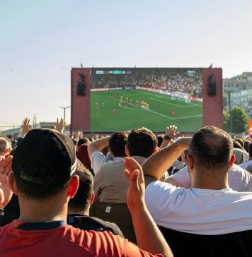 Hochbahn gönnt WM-Fans 20 Minuten Nachspielzeit Eine Menge an Menschen steht vor einem großen Bildschirm, auf dem ein Fußball-Spiel gezeigt wird.