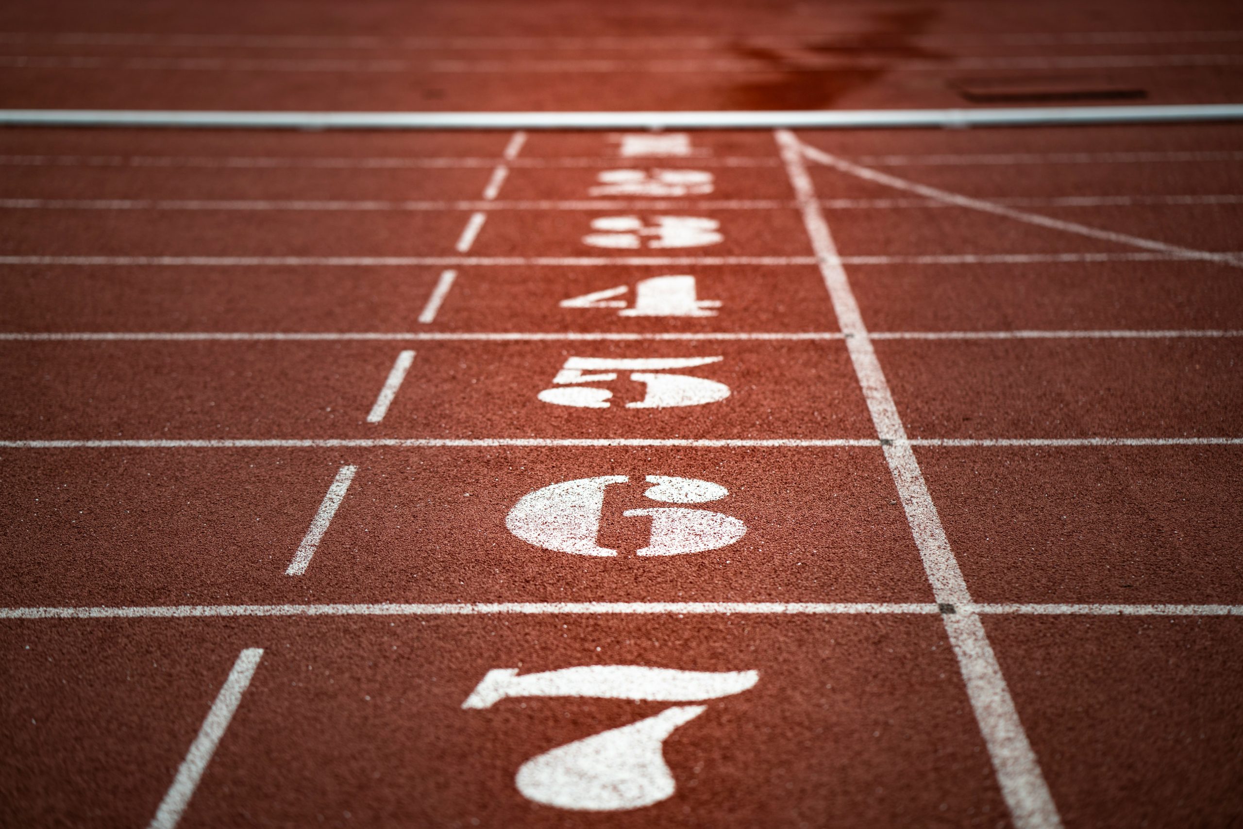 adi-goldstein-7BpeiA0bhxs-unsplash Eine Tartanbahn mit den Startzonen von eins bis sieben durchnummeriert.