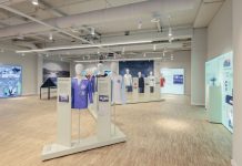 „Warum ist sie nicht gegangen?“ Sport im Nationalsozialismus Der Ausstellungsraum mit Informationstafeln an den Wänden und Figuren mit Trikots in der Mitte des Raumes.