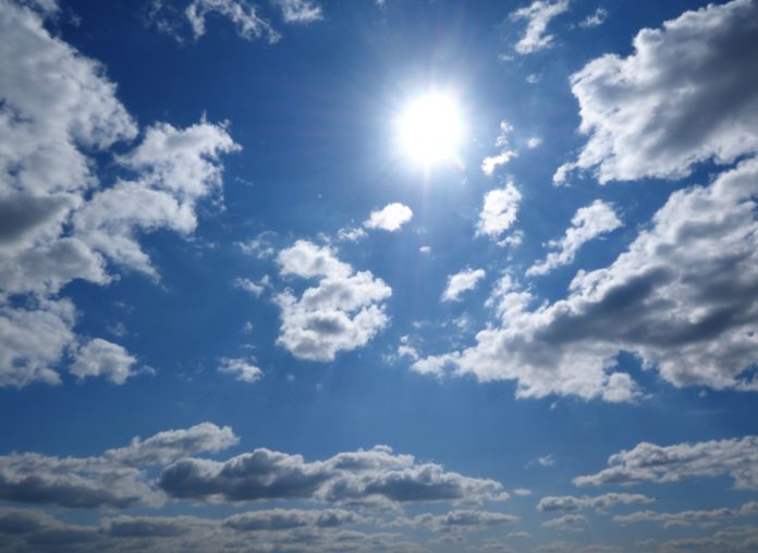 Sonne strahlt am blauen Himmel mit ein paar Wolken.