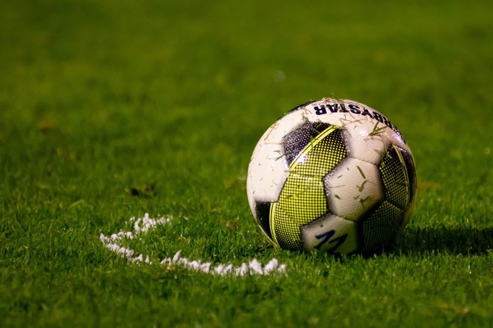 Ein Fußball liegt auf einem grünen Rasen.