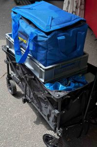 Auf dem Bild sieht man einen Bollerwagen, in dem eine leere blaue IKEA Tüte, leere Metro Tüte und eine leere graue Kiste zu sehen sind.
