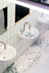 Blick von oben: Scherben der zerschlagenen Spiegelscheibe liegen in Waschbecken und auf dem Boden der nachgebauten Toilettenanlage auf Kampnagel.