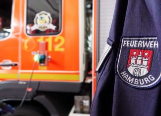 Zwei Autos brennen in Bramfeld – Ursache unklar Uniform der Hamburger Feuerwehr vor einem orangenen Feuerwehr-Truck. News zu einem Brand in Bramfeld – Ursache unklar.