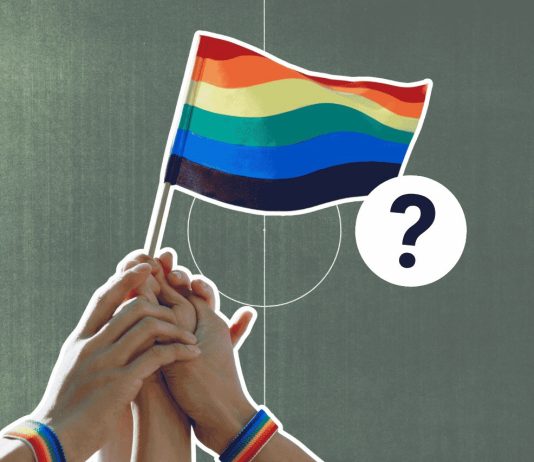Fußball verbindet? So queerfreundlich ist die Männer-WM Im Vordergund ist eine Regenbogen-Flagge zu sehen. Im Hintergrund ist ein Fußball-Stadion.