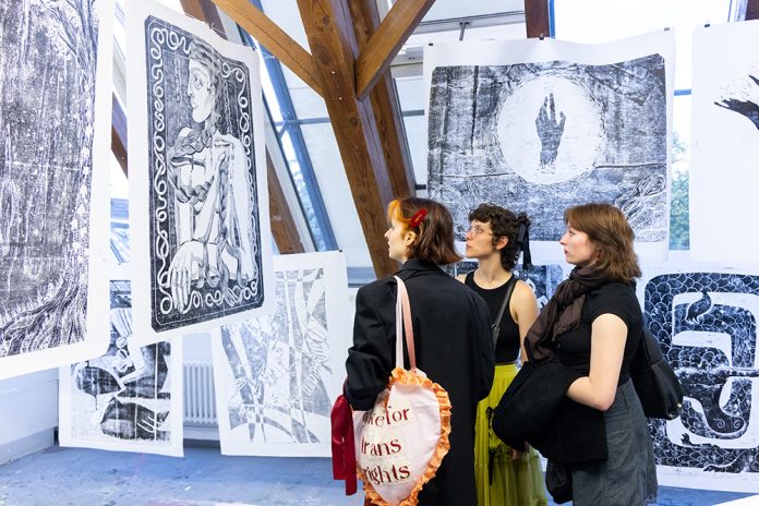 Drei Frauen gucken sich Kunstwerke an.