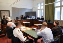 Schuldig: Urteil gegen Hamburger Polizisten In einem Gerichtsaal sitzen Personen an Tischen zueinander, wobei drei Gesichter zesniert sind.