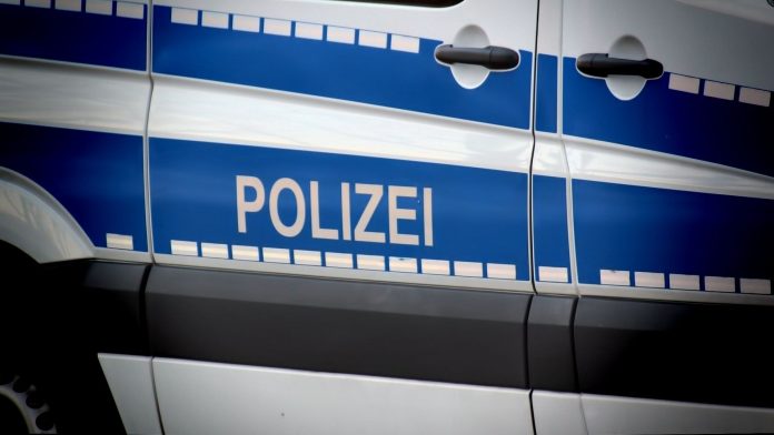 Ein Teil eines Polizeiwagens ist zu sehen. Im Fokus des Bildes ist die Aufschrift „Polizei“ des Autos.
