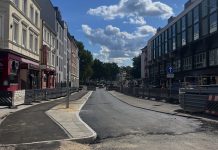 Erneut Verkehrseinschränkungen am Eppendorfer Marktplatz Das Bild zeigt eine Straße am Eppendorfer Marktplatz. Sie ist verschmutzt von Bauarbeiten. Links und rechts der Straße sind Wohnhäuser und Geschäfte zu sehen. Der Himmel ist blau. Die Sonne scheint.