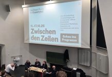 Einblicke in den Journalismus In einem Hörsaal wird Schrift an die Wand projiziert:"Hamburger Woche der Pressefreiheit" und "Zwischen den Zeilen". Vor dem Bildschirm steht ein Tisch an dem viert leute versammelt sind und diskutieren. Foto: Patricia Schnoor