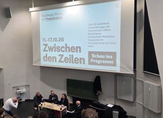 Einblicke in den Journalismus In einem Hörsaal wird Schrift an die Wand projiziert:"Hamburger Woche der Pressefreiheit" und "Zwischen den Zeilen". Vor dem Bildschirm steht ein Tisch an dem viert leute versammelt sind und diskutieren. Foto: Patricia Schnoor